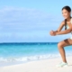 Mujer joven deportistas realizando ejercicio en la arena de playa paradisiaca